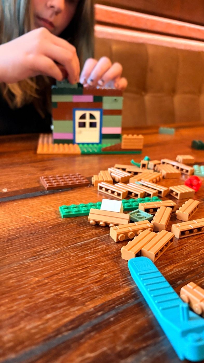 Grünes Lego-Haus mit blauem Fenster mitten im Bauprozess