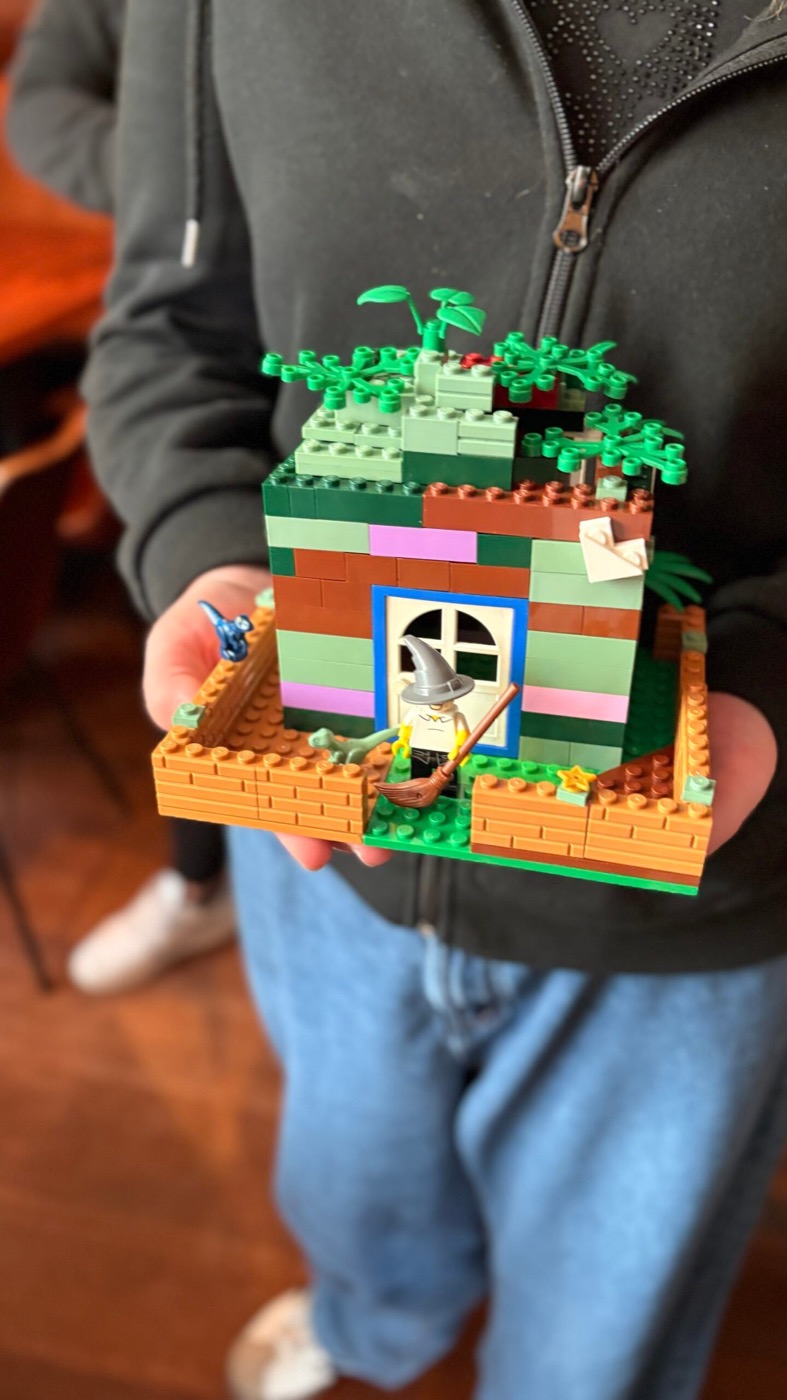 Mädchen hält das fertige Lego-Hexenhäuschen stolz in die Kamera