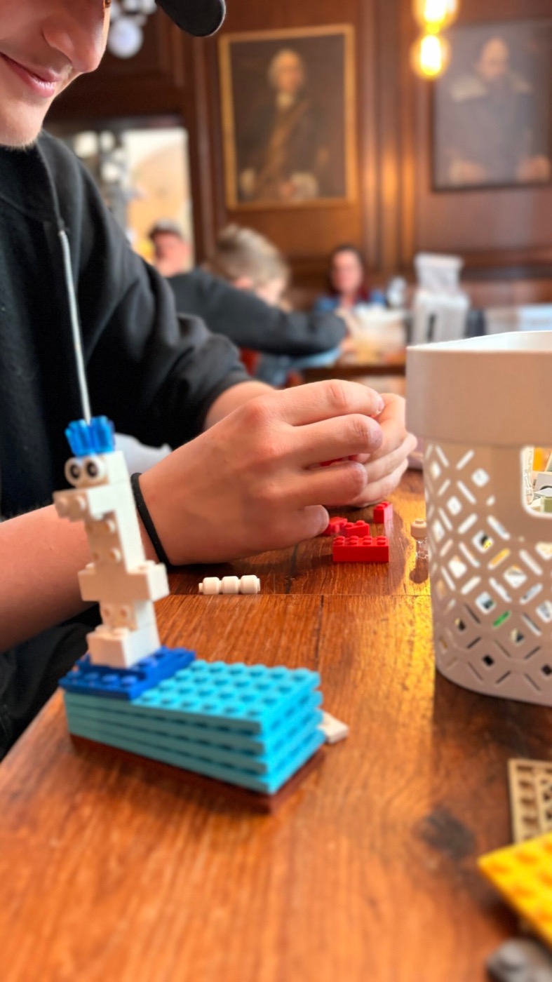 Junge baut einen Lego-Roboter, im Hintergrund die barocken Gemälde des Ratskellers