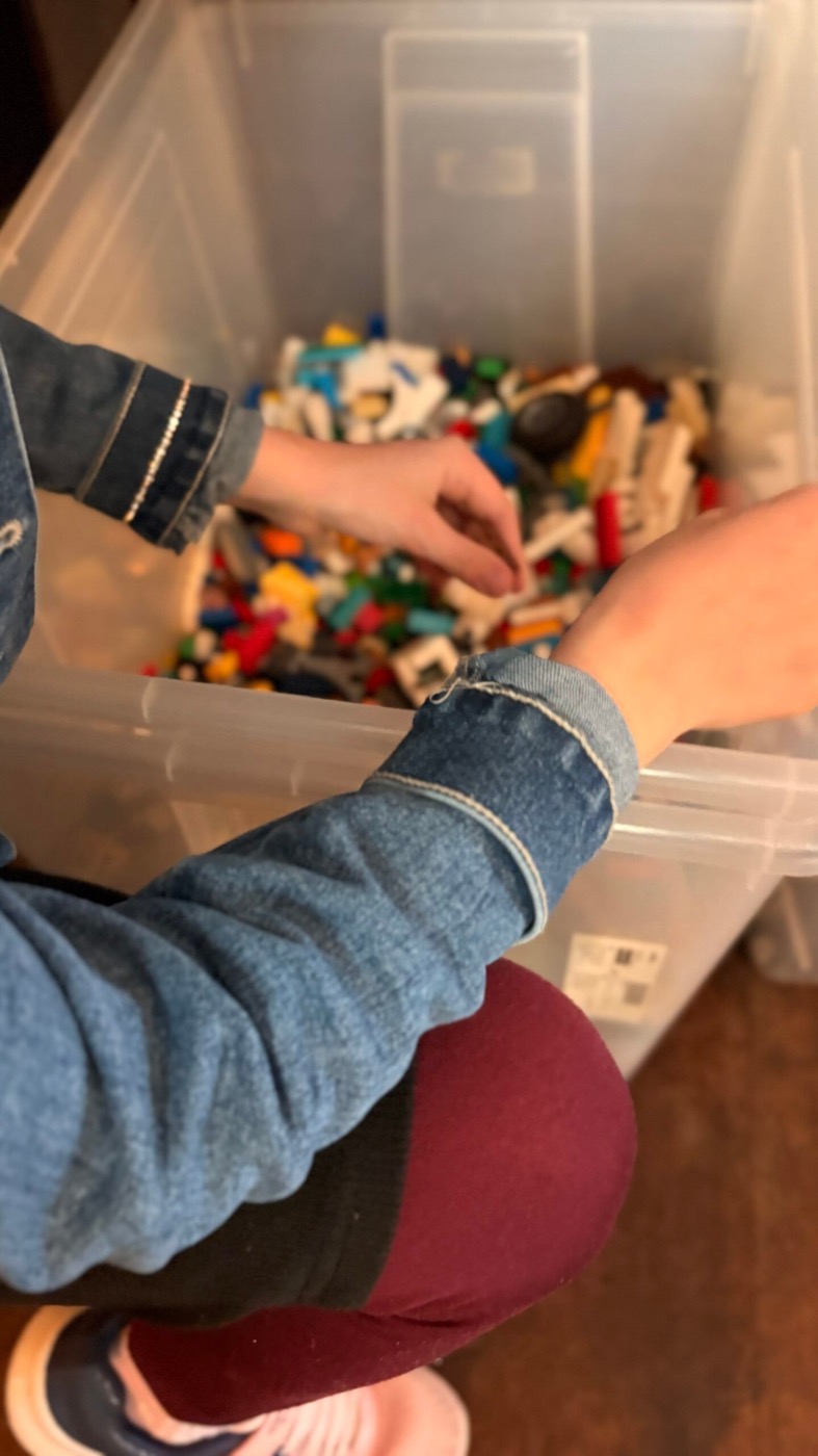 Kind wühlt in einer großen Kiste voller Lego-Steinen