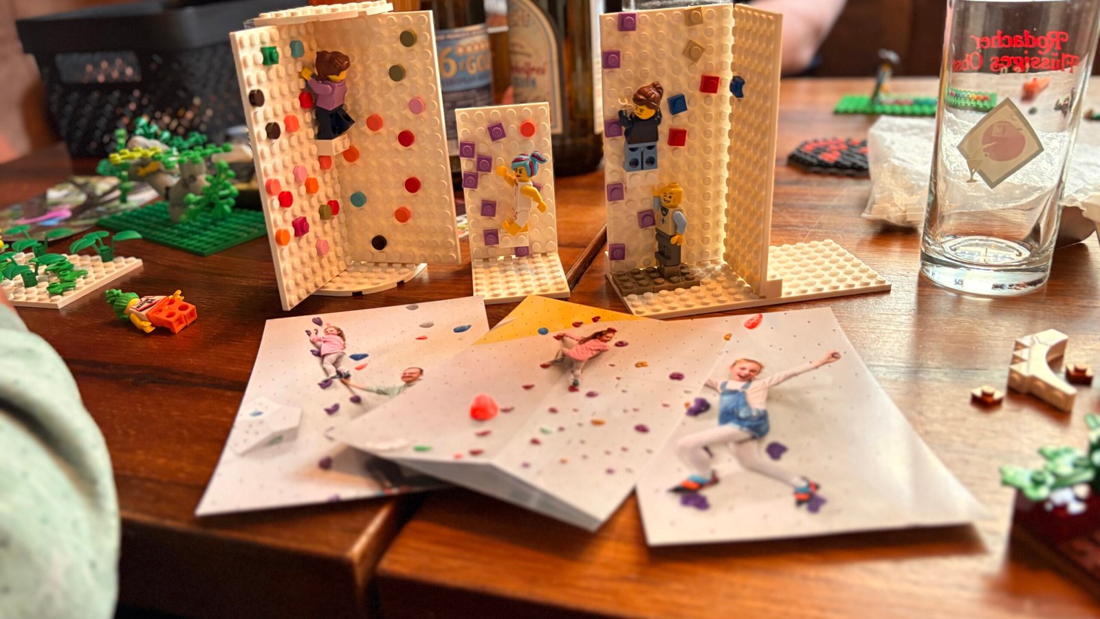 Mehrere Lego-Kletterszenen mit kleinen Kletter-Minifiguren und gemalten Karten neben Bierflaschen