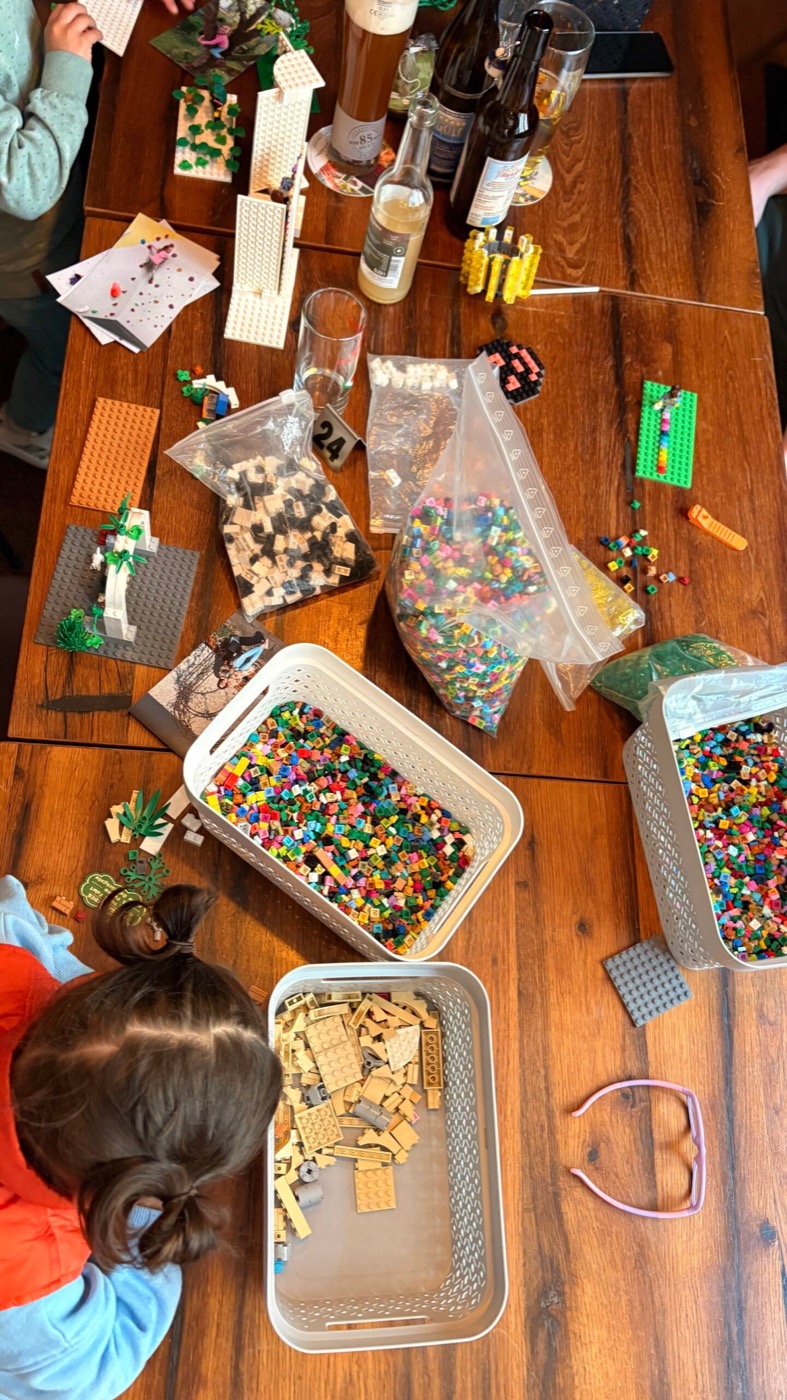 Tisch voller Lego-Bausteine, Bügelperlen und Tüten beim Workshop