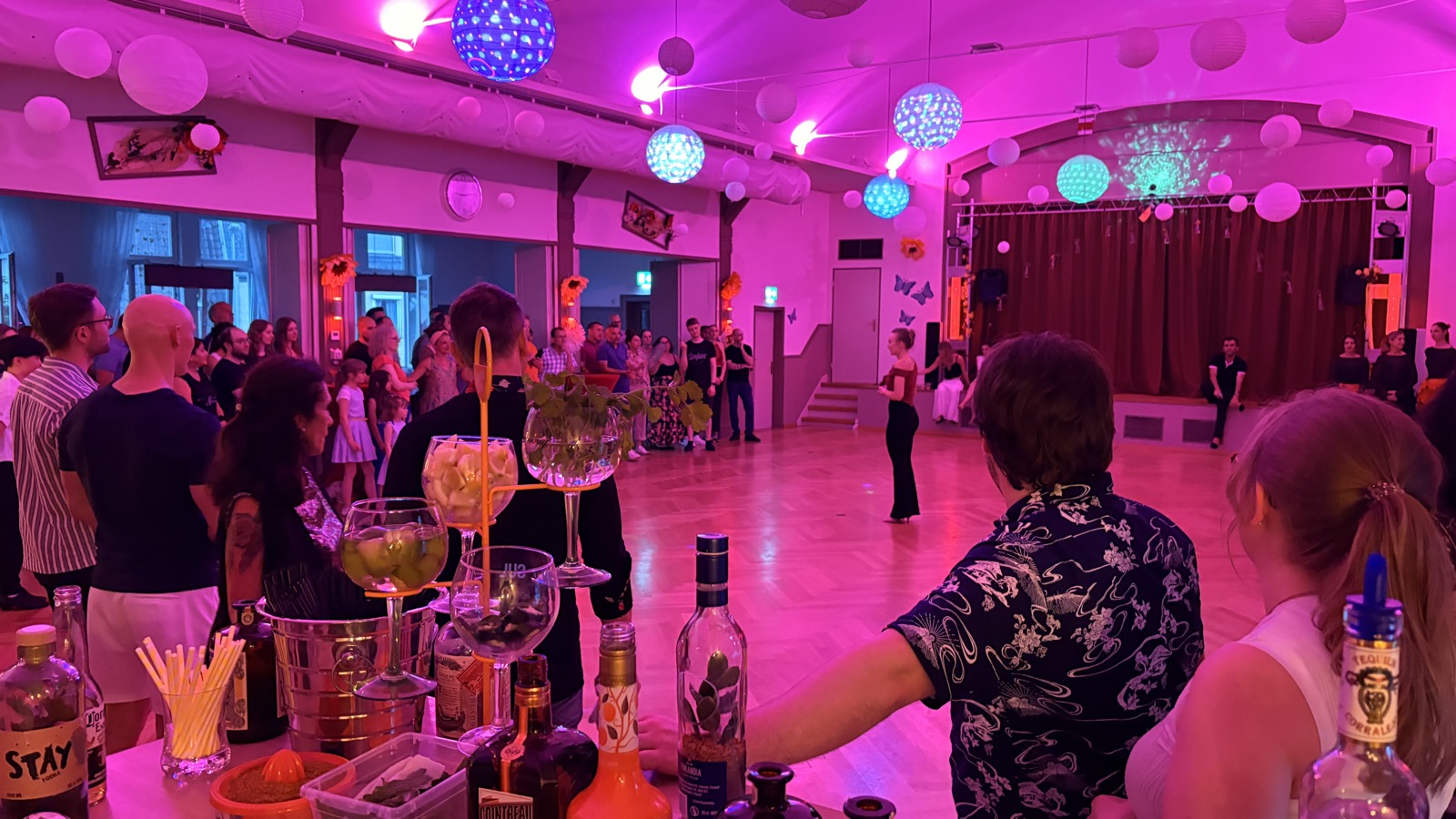 Blick von der Casa-Blumen-Bar über die Tanzfläche der Fiesta Latina, Sonnenblumen und garnierte Gläser im Vordergrund
