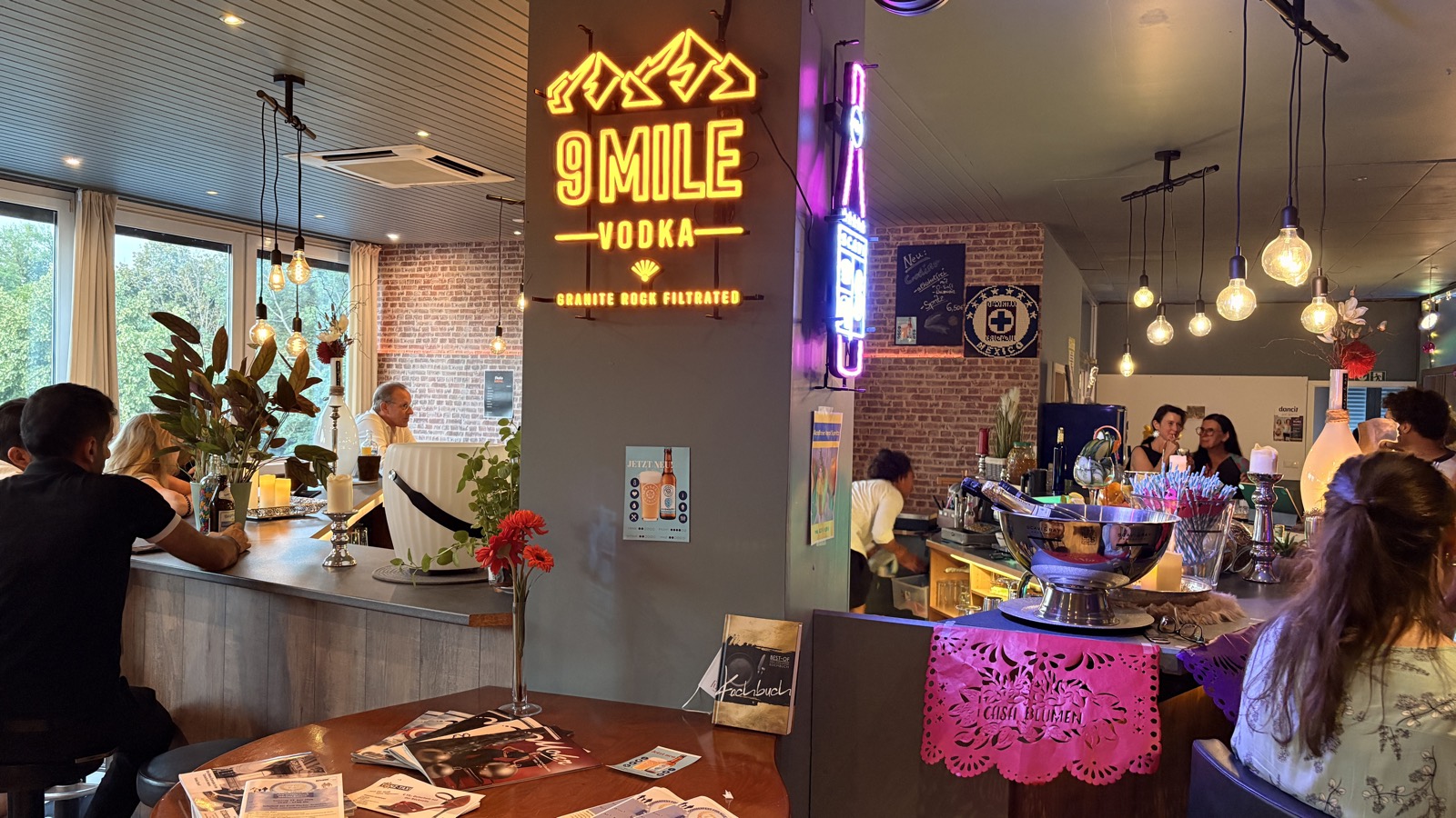 Die Cocktailbar von Casa Blumen bei der Noche Latina mit Neon-Schild, Edison-Lampen und pinkem Papel Picado