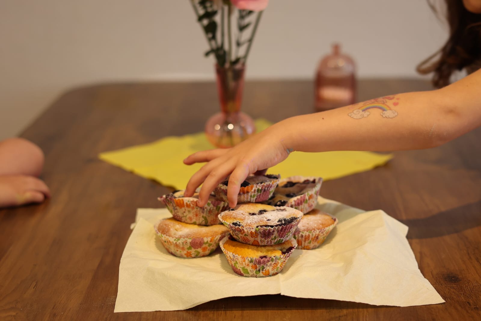 Kinderhand greift nach frisch gebackenen Blaubeer-Muffins